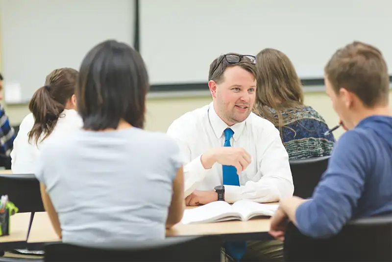 A businessman sitting at a table conversing with his peers
