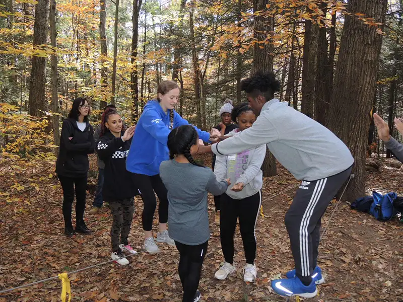 A group of children and young adults playing group activities in the woods