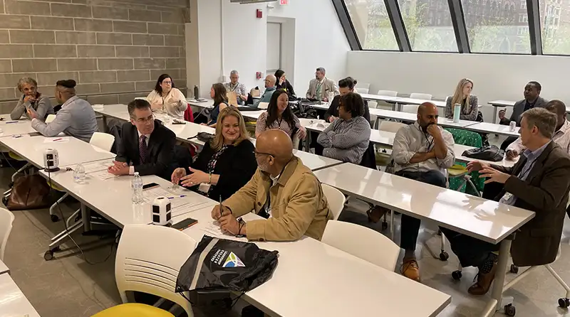 Executive Orientation Members in rows of desks collaborating with each other