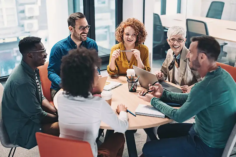 A group of colleagues sitting at a round table talking with each other