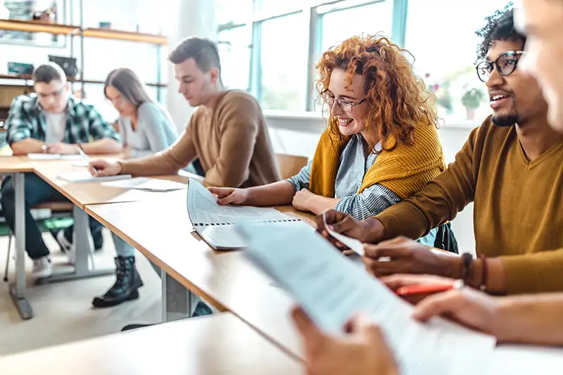 Young professionals sitting at a table together with booklets