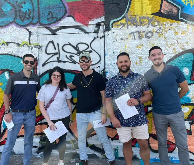 A group of LGH program members smiling infront of a colorful graffiti wall in Hartford,CT