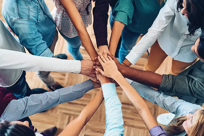 A diverse group of people putting their hands together in a circle